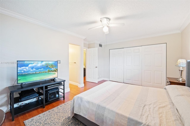 bedroom featuring ceiling fan, a textured ceiling, hardwood / wood-style flooring, ornamental molding, and a closet