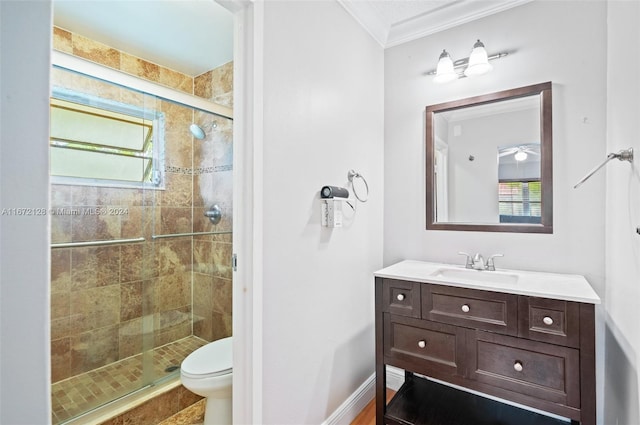 bathroom featuring vanity, toilet, crown molding, and a shower with shower door