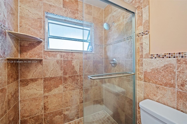 bathroom with toilet, an enclosed shower, and tile walls