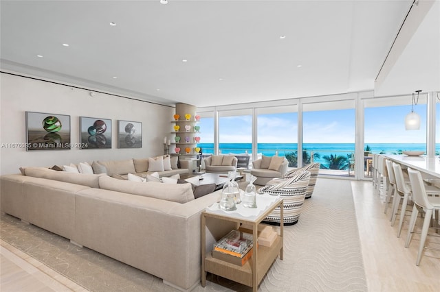 living room with a water view, floor to ceiling windows, and light hardwood / wood-style floors