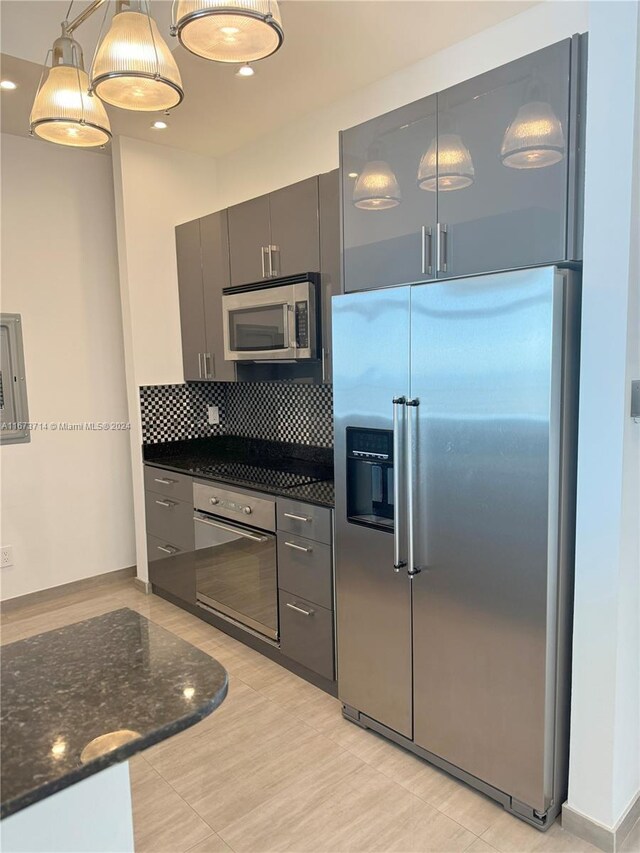 325 S Biscayne Blvd Unit 19, Miami, FL 33131 - kitchen featuring stainless steel appliances, decorative backsplash, dark stone countertops, decorative light fixtures, and baseboards