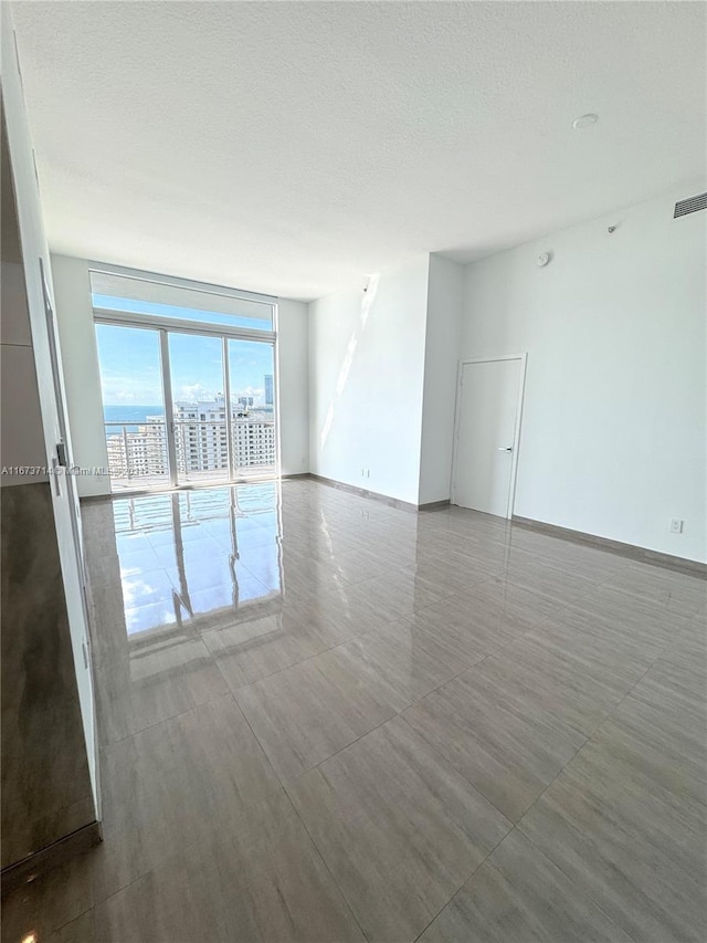 unfurnished room featuring a textured ceiling and floor to ceiling windows