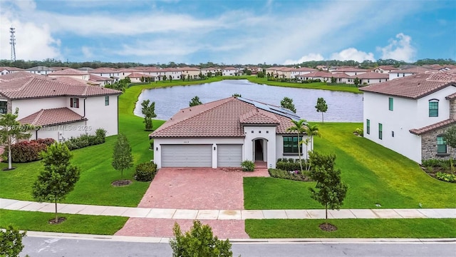 mediterranean / spanish home with a front lawn, a water view, a garage, and solar panels