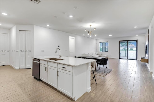 kitchen with dishwasher, a kitchen island with sink, an inviting chandelier, white cabinets, and sink