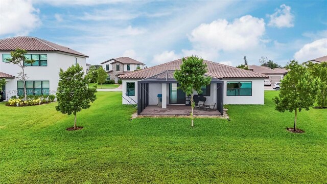 back of property featuring a lawn, glass enclosure, and a patio area