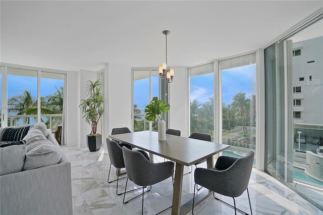 dining area featuring an inviting chandelier and a wall of windows