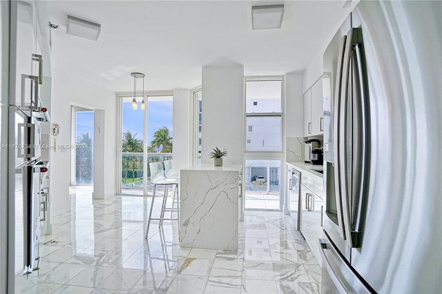 kitchen with stainless steel fridge, a breakfast bar, decorative light fixtures, white cabinets, and floor to ceiling windows