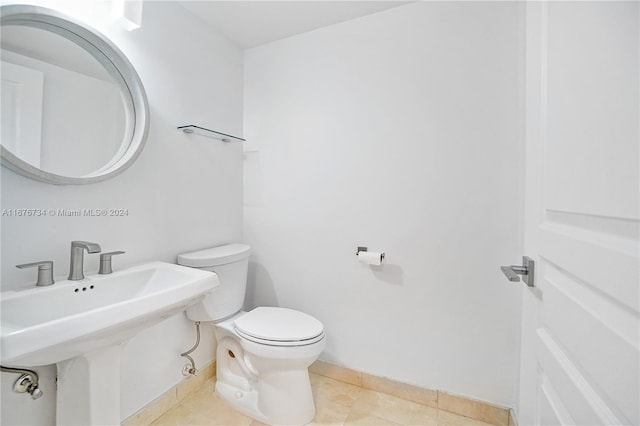 bathroom with toilet, sink, and tile patterned floors