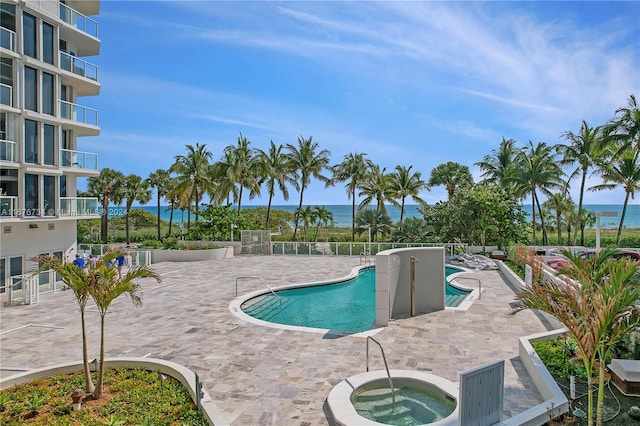 view of pool with a patio area, a community hot tub, and a water view