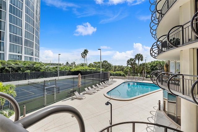 view of pool with a patio and tennis court