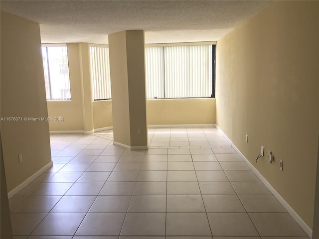spare room with a textured ceiling, baseboards, and light tile patterned floors