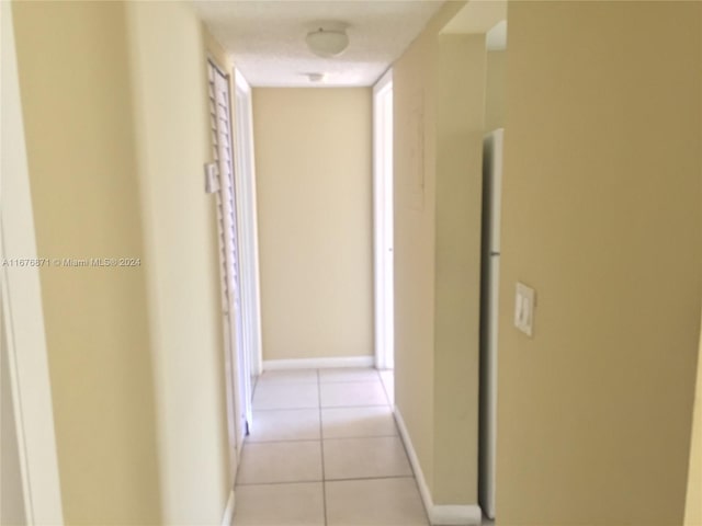 corridor with light tile patterned floors and baseboards