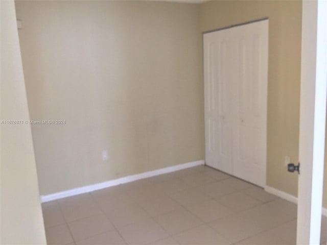 empty room featuring baseboards and light tile patterned floors