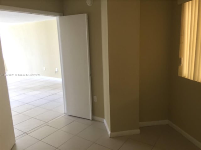 unfurnished room with light tile patterned floors and baseboards
