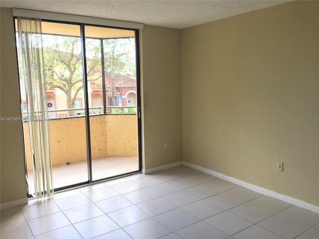 spare room featuring baseboards, tile patterned flooring, and a textured ceiling
