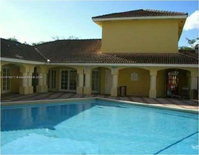 back of house featuring a tile roof and an outdoor pool