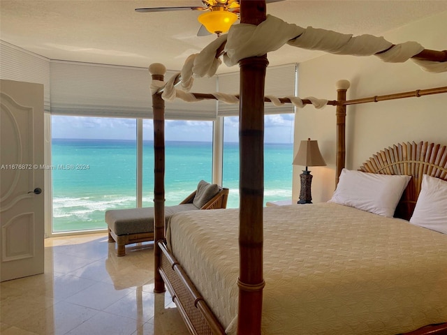 bedroom featuring multiple windows, a water view, a beach view, and ceiling fan