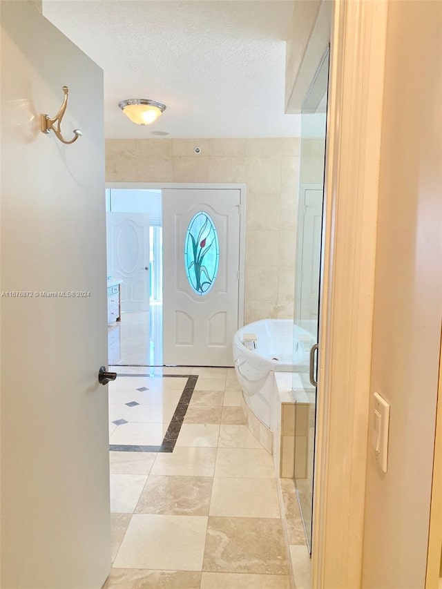 tiled foyer with tile walls and a textured ceiling