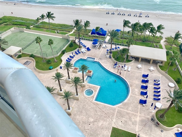 view of swimming pool featuring a water view, a view of the beach, and a patio