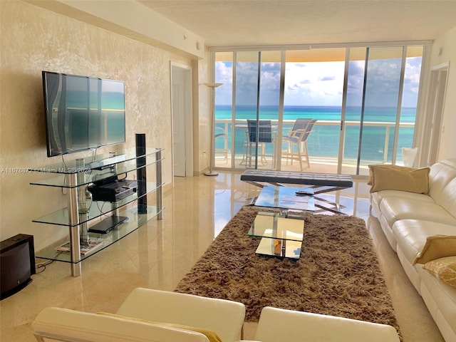 living room with expansive windows, a view of the beach, and a water view