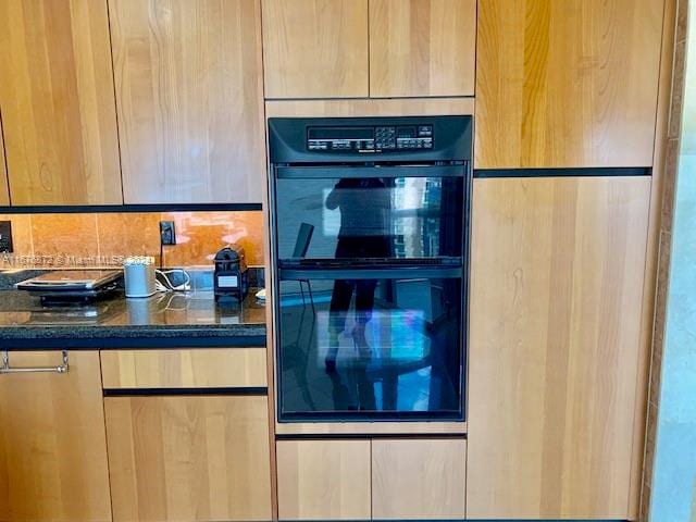 kitchen with black double oven and dark stone counters