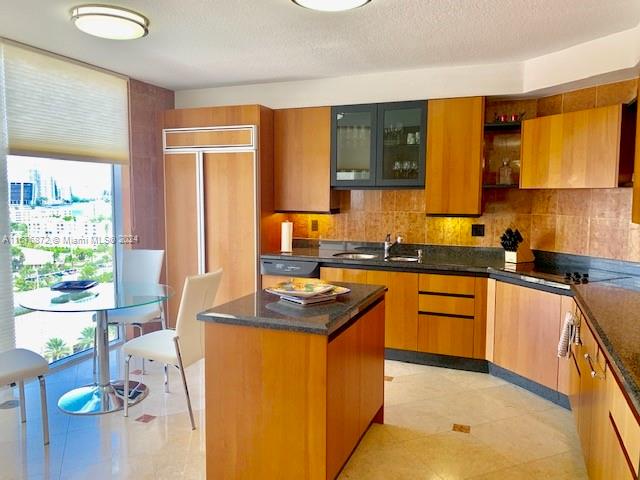 kitchen with sink, dishwasher, backsplash, a center island, and light tile patterned floors