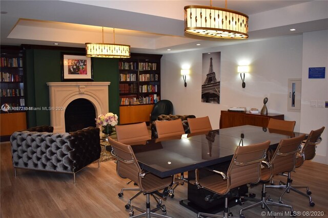 dining space with hardwood / wood-style floors and a raised ceiling