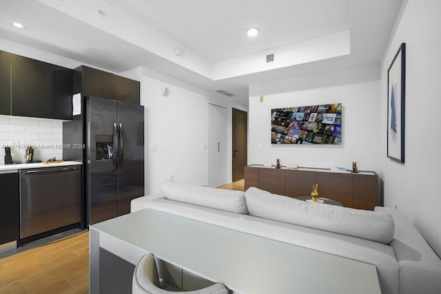living room featuring recessed lighting, visible vents, light wood finished floors, and a raised ceiling