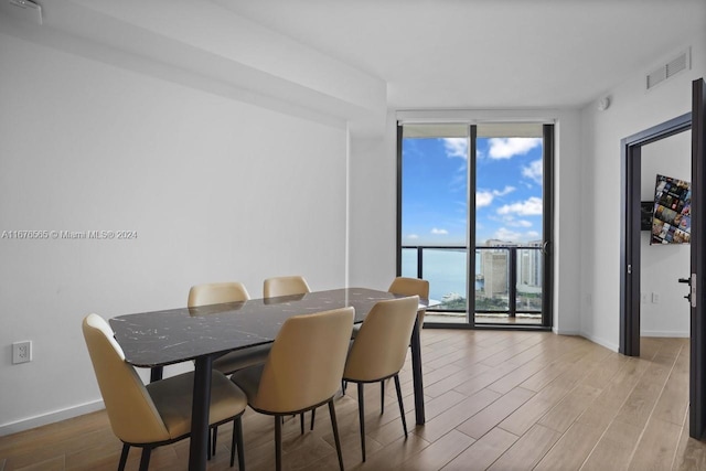 dining room featuring plenty of natural light, light wood-type flooring, visible vents, and floor to ceiling windows