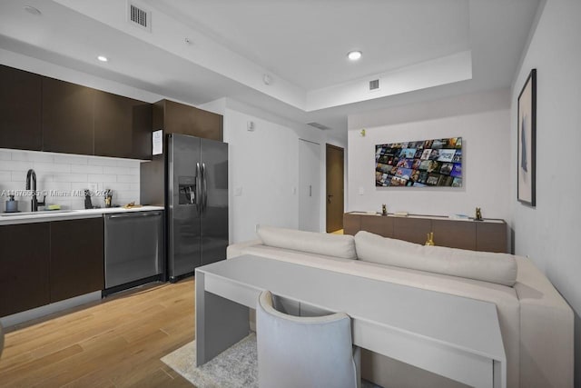 interior space with sink, backsplash, dark brown cabinets, stainless steel appliances, and light hardwood / wood-style flooring