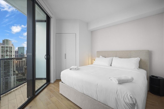 bedroom with wood finished floors and a view of city