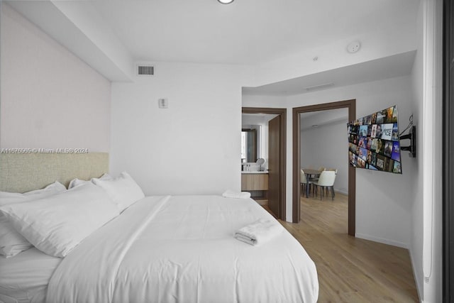 bedroom featuring light hardwood / wood-style flooring and ensuite bath