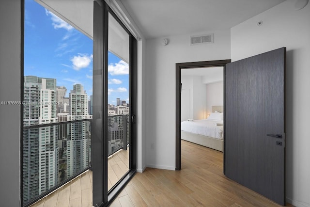interior space featuring wood finished floors, expansive windows, a city view, baseboards, and visible vents
