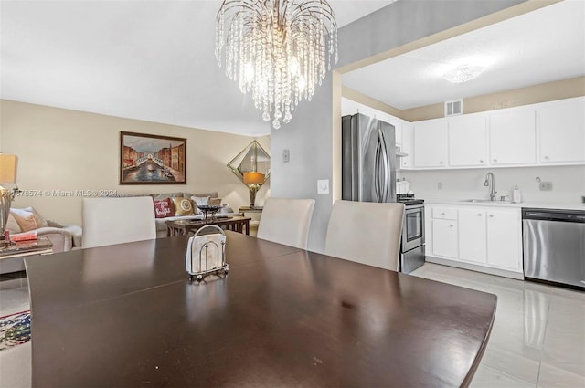 dining space featuring sink, light tile patterned flooring, and a chandelier