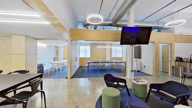 game room featuring a towering ceiling and concrete flooring