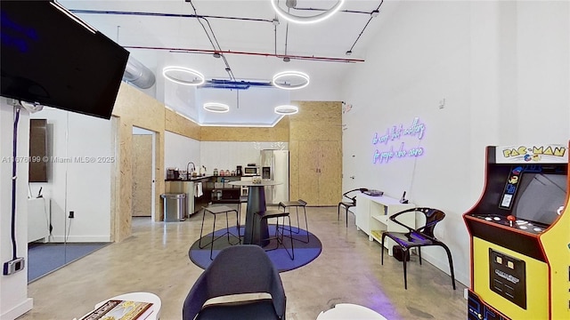 interior space featuring a towering ceiling, sink, and concrete floors