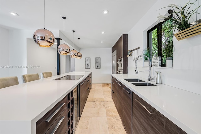 kitchen featuring black electric stovetop, sink, stainless steel oven, pendant lighting, and a breakfast bar