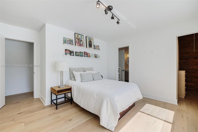 bedroom with ensuite bathroom and light hardwood / wood-style flooring