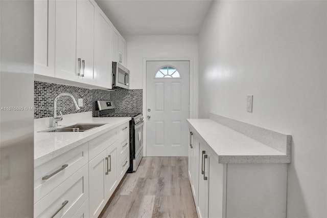 kitchen featuring light stone countertops, sink, light wood-type flooring, white cabinetry, and stainless steel appliances