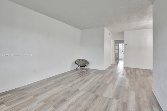 unfurnished room featuring light hardwood / wood-style floors and a textured ceiling