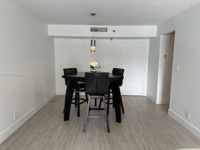 dining room featuring light hardwood / wood-style flooring and a textured ceiling