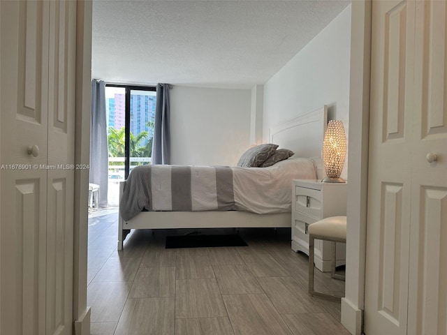 bedroom featuring expansive windows, a textured ceiling, and access to exterior