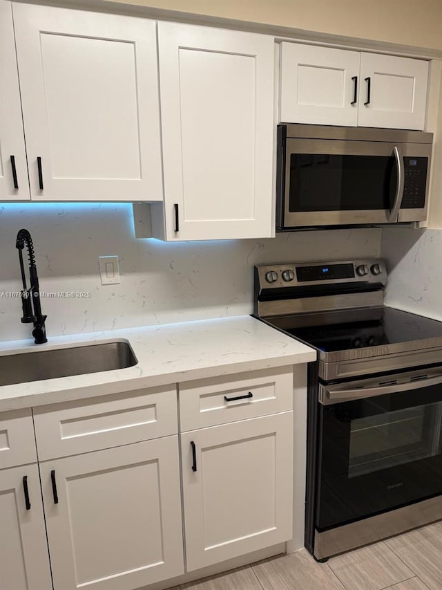 3300 NE 192nd St Unit 414, Aventura, FL 33180 - kitchen featuring stainless steel appliances, white cabinets, and light stone countertops