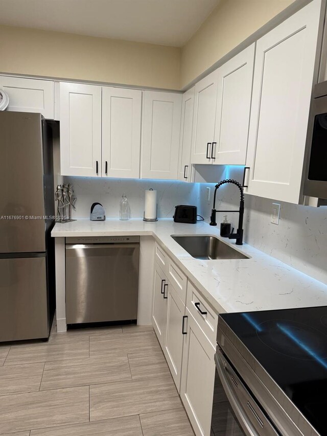 3300 NE 192nd St Unit 414, Aventura, FL 33180 - kitchen featuring appliances with stainless steel finishes, white cabinets, and light stone countertops