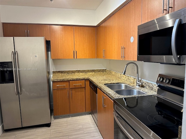 kitchen featuring light stone countertops, sink, and appliances with stainless steel finishes