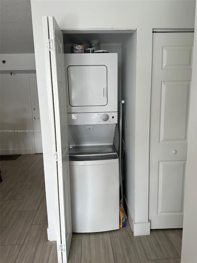 laundry area with a textured ceiling and stacked washer and clothes dryer