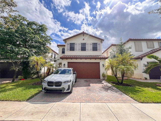 mediterranean / spanish home featuring a front yard and a garage