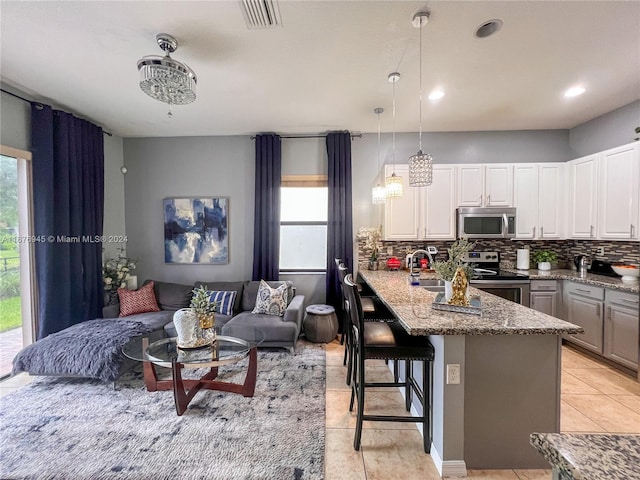 kitchen featuring backsplash, visible vents, appliances with stainless steel finishes, white cabinets, and a peninsula