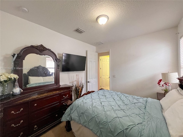 bedroom with carpet floors, a textured ceiling, and visible vents