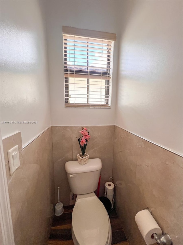 bathroom with tile walls and toilet